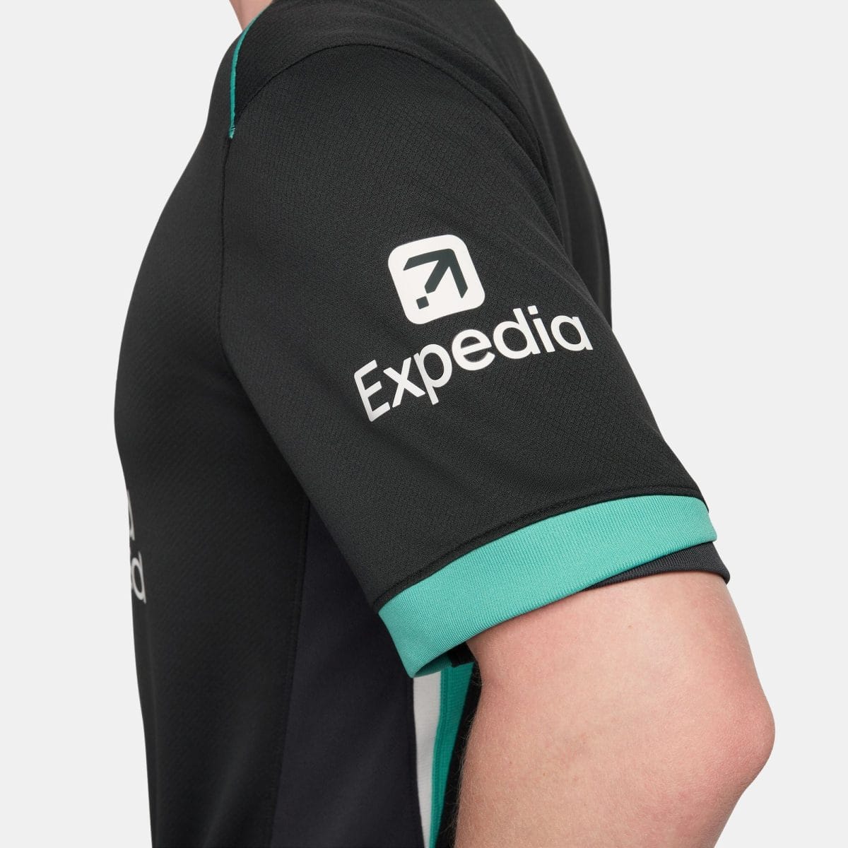 Close-up of a black sports jersey sleeve with teal cuff and a white logo on the upper arm.