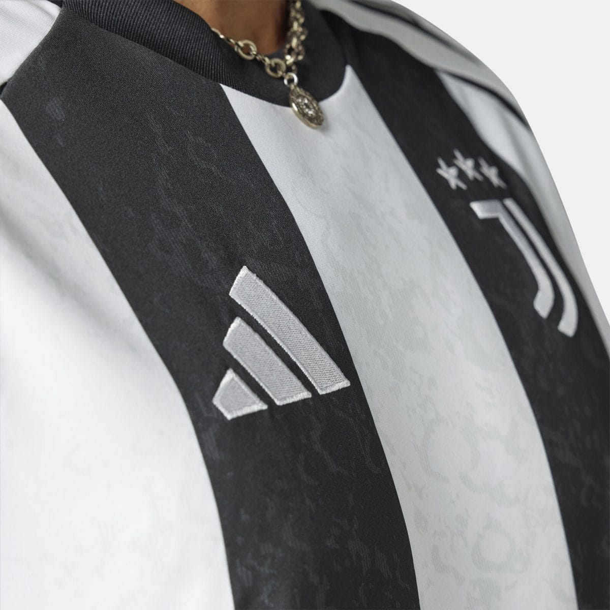 Close-up of a black-and-white striped fabric with a silver pendant necklace resting on the chest.