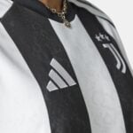 Close-up of a black-and-white striped fabric with a silver pendant necklace resting on the chest.
