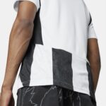 Close-up of a person’s arm and torso wearing a white garment with bold black vertical stripes; part of a patterned outfit is visible.