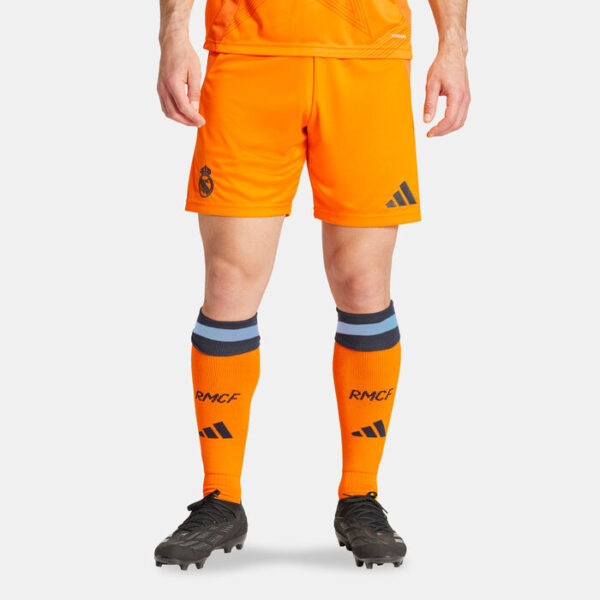 Lower-body view of a footballer in bright orange shorts and matching orange socks with RMCF letters and Adidas logos, wearing dark football boots.