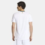 Back view of a man wearing a white polo shirt with a green-trimmed collar and a small gold palm logo on the upper back.