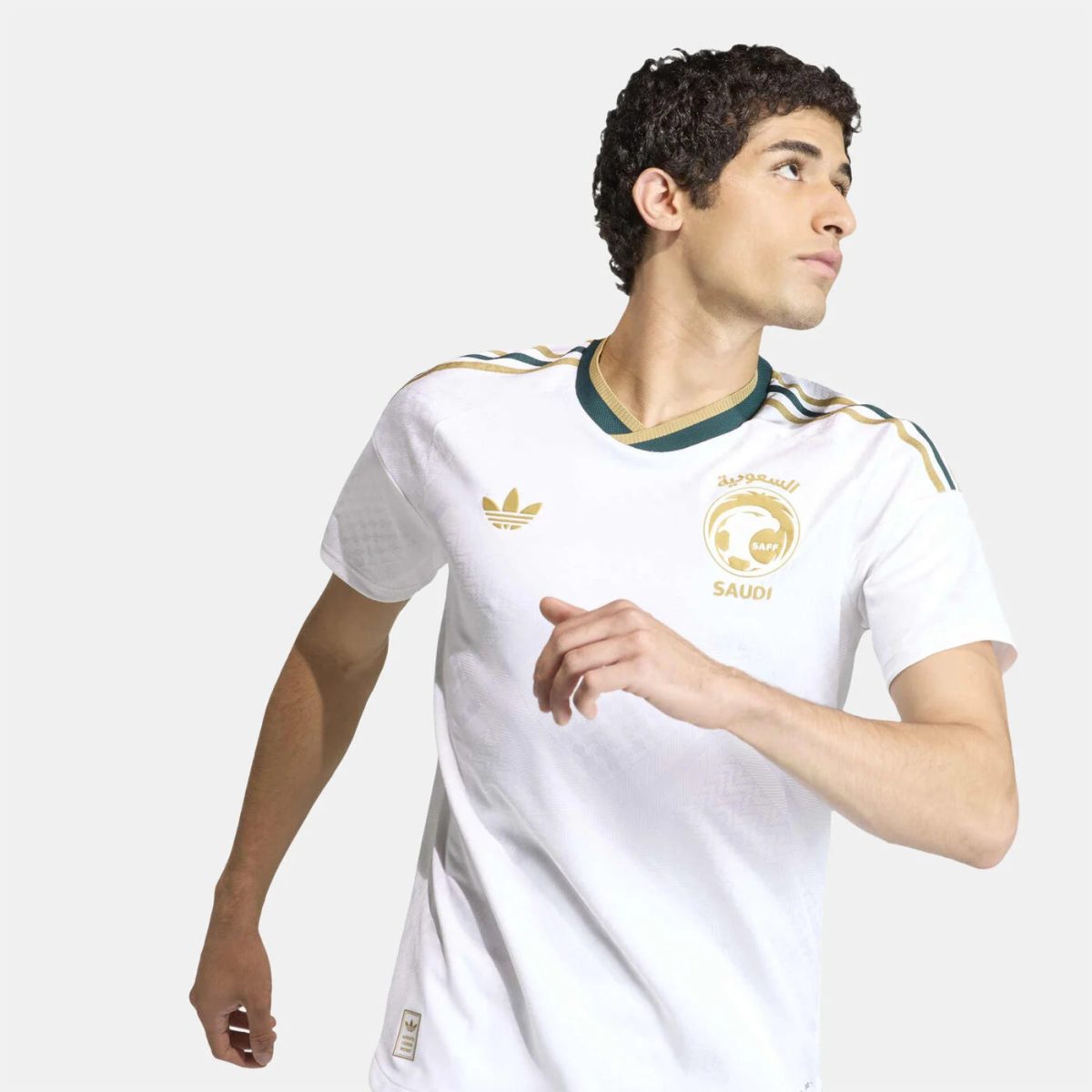 Young man wearing a white Saudi Arabia soccer jersey runs to the right, looking ahead.3c33a7
