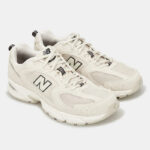 Pair of white New Balance athletic sneakers with mesh panels and black NB logos on the sides.