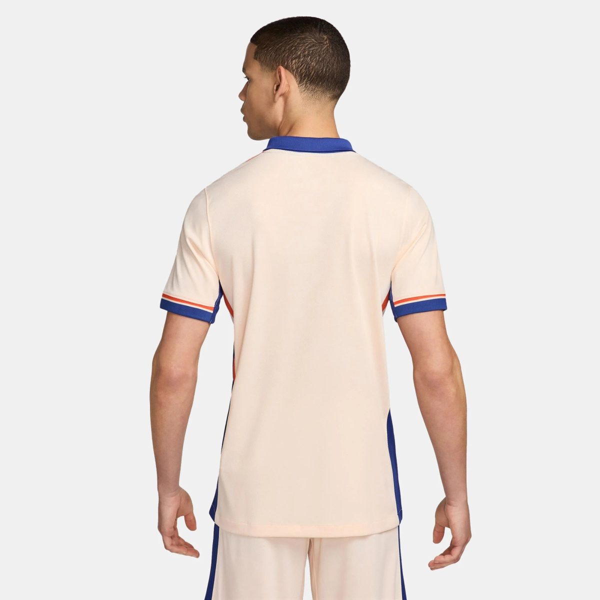 Back view of a person wearing a beige sports jersey with blue trim and red accents on the sleeves