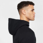 Profile view of a young man wearing a black hoodie against a light background.
