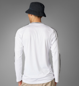 Person seen from behind wearing a white long-sleeve shirt with black piping and a dark bucket hat.