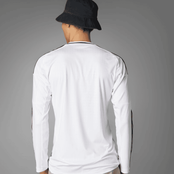 Person seen from behind wearing a white long-sleeve shirt with black piping and a dark bucket hat.