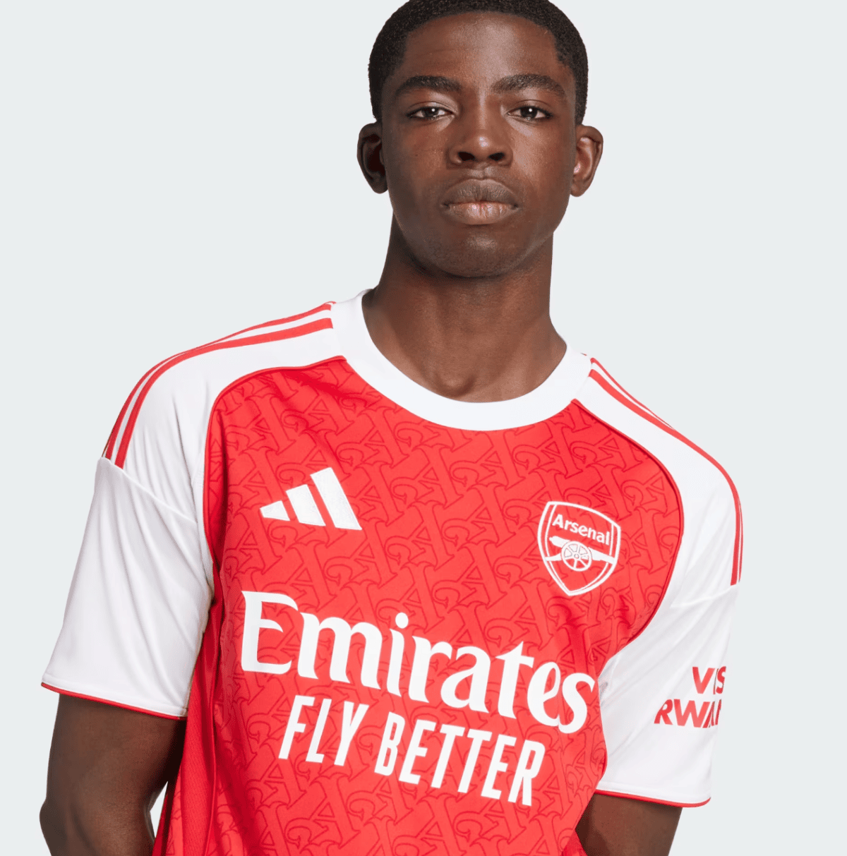 Portrait of a young man facing the camera, wearing a red and white Arsenal jersey with the Emirates Fly Better sponsor and crest visible.