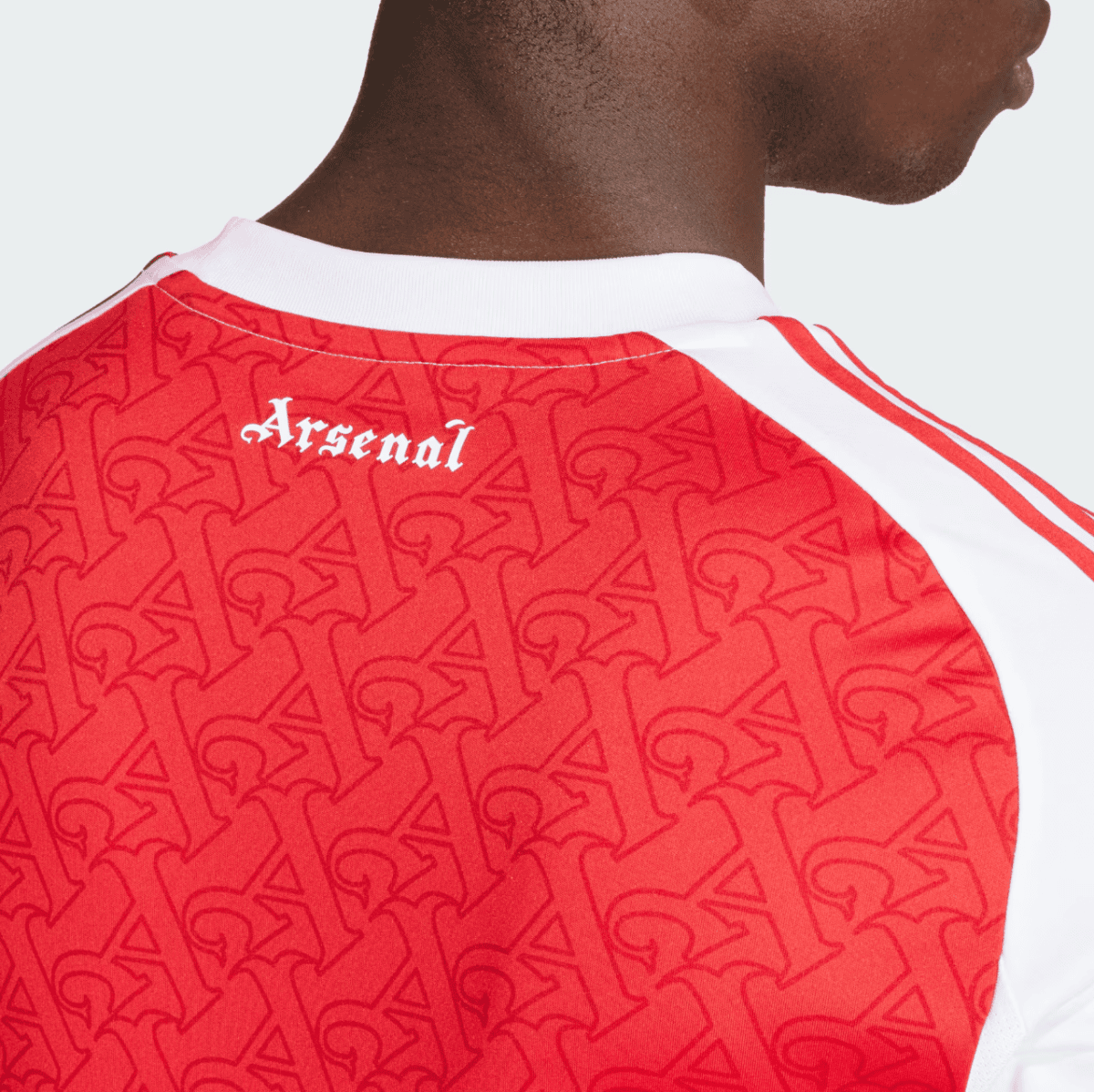 Back view of a person wearing a red Arsenal football jersey with a white collar and repeating pattern across the fabric, 'Arsenal' text near the neckline.
