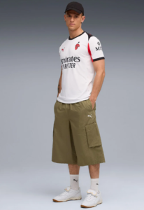 Male model wearing a white soccer jersey with black cap and olive cargo shorts, posing against a gray backdrop.