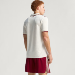 Person shown from behind wearing a white polo shirt with burgundy trim and maroon shorts with white stripes, on a neutral backdrop.
