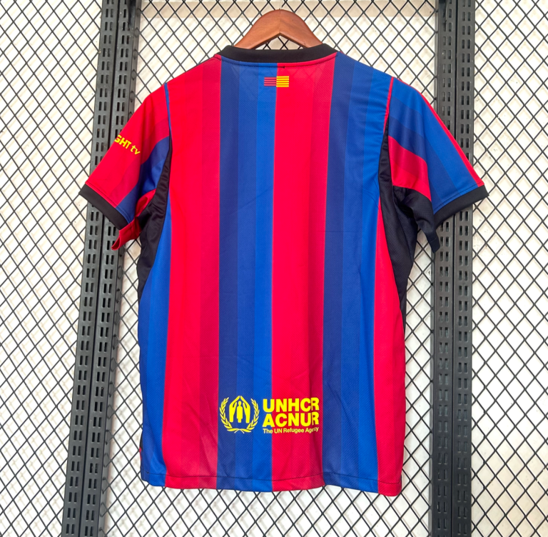 Screenshot2026-01-24at12.35.03-768x752-1 | UAE SPORT STORE Red and blue vertical-striped sports jersey hanging on a wooden hanger against a metal grid; UNHCR logo at the bottom and a small flag near the collar.
