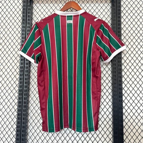 Back of a maroon and green striped soccer jersey on a wooden hanger against a metal grid background, white trim at collar and sleeves