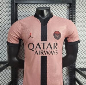 Pink Paris Saint-Germain football jersey on a mannequin, with Qatar Airways sponsor and black vertical stripe down the center.