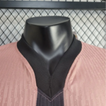 Mannequin bust wearing a pink ribbed cardigan with a black V-neck collar and inner black layer.