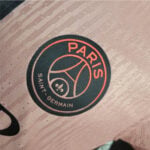 Close-up of a round Paris Saint-Germain patch on pink fabric.