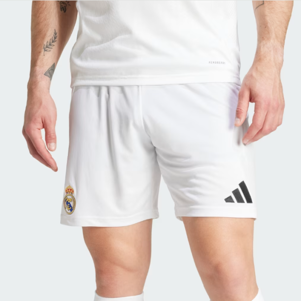 Person wearing white Real Madrid soccer shorts with club crest on the left leg and Adidas logo on the right.