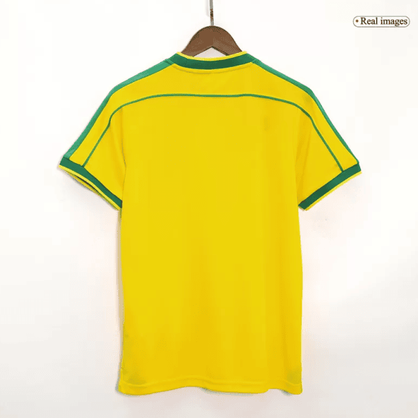 Back view of a bright yellow soccer jersey with green piping along shoulders and sleeves, on a wooden hanger