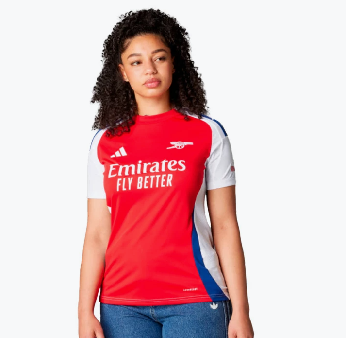Screenshot_2024-07-26_184030 Female model wearing Arsenal away jersey: red body, white sleeves, blue side panels, Emirates Fly Better logo.