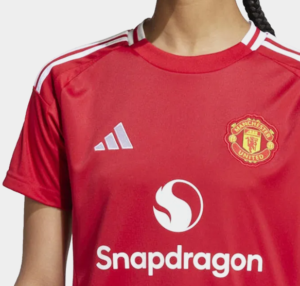 Close-up of a red Manchester United football jersey featuring the Adidas logo, the Snapdragon sponsor, and the team crest on the chest.