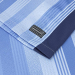 Close-up of a blue plaid shirt sleeve with a dark blue cuff and a small black tag reading 'Engineered Garments'.