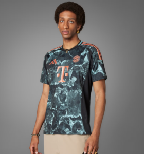 Young man wearing a navy teal tie-dye Adidas Bayern Munich soccer jersey with orange accents and sponsor logo.