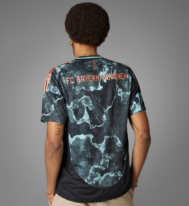 Back view of a person wearing a blue marble-patterned FC Bayern München jersey with orange lettering on the back.