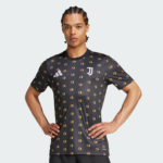 Black athletic t-shirt with a yellow donut pattern, featuring Adidas logo on the chest and a Juventus crest; model stands with hands on hips.