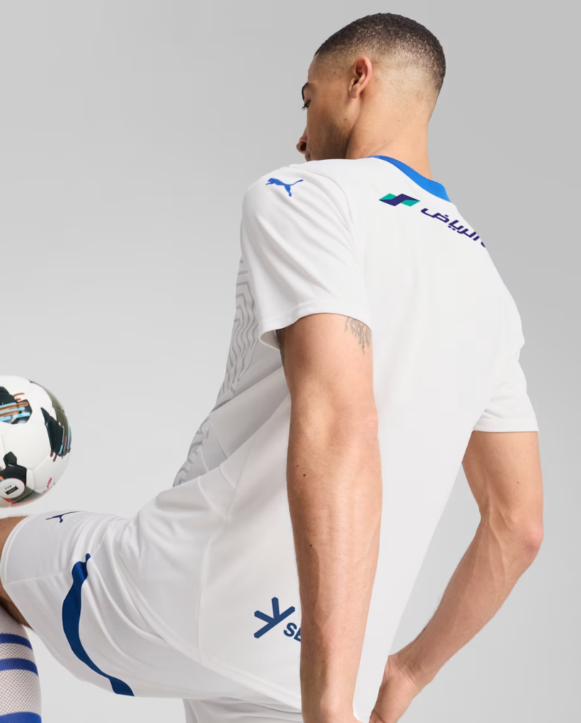 Screenshot_2024-09-04_203301 | UAE SPORT STORE Back view of a soccer player in a white kit with blue accents, balancing a soccer ball at the hip.