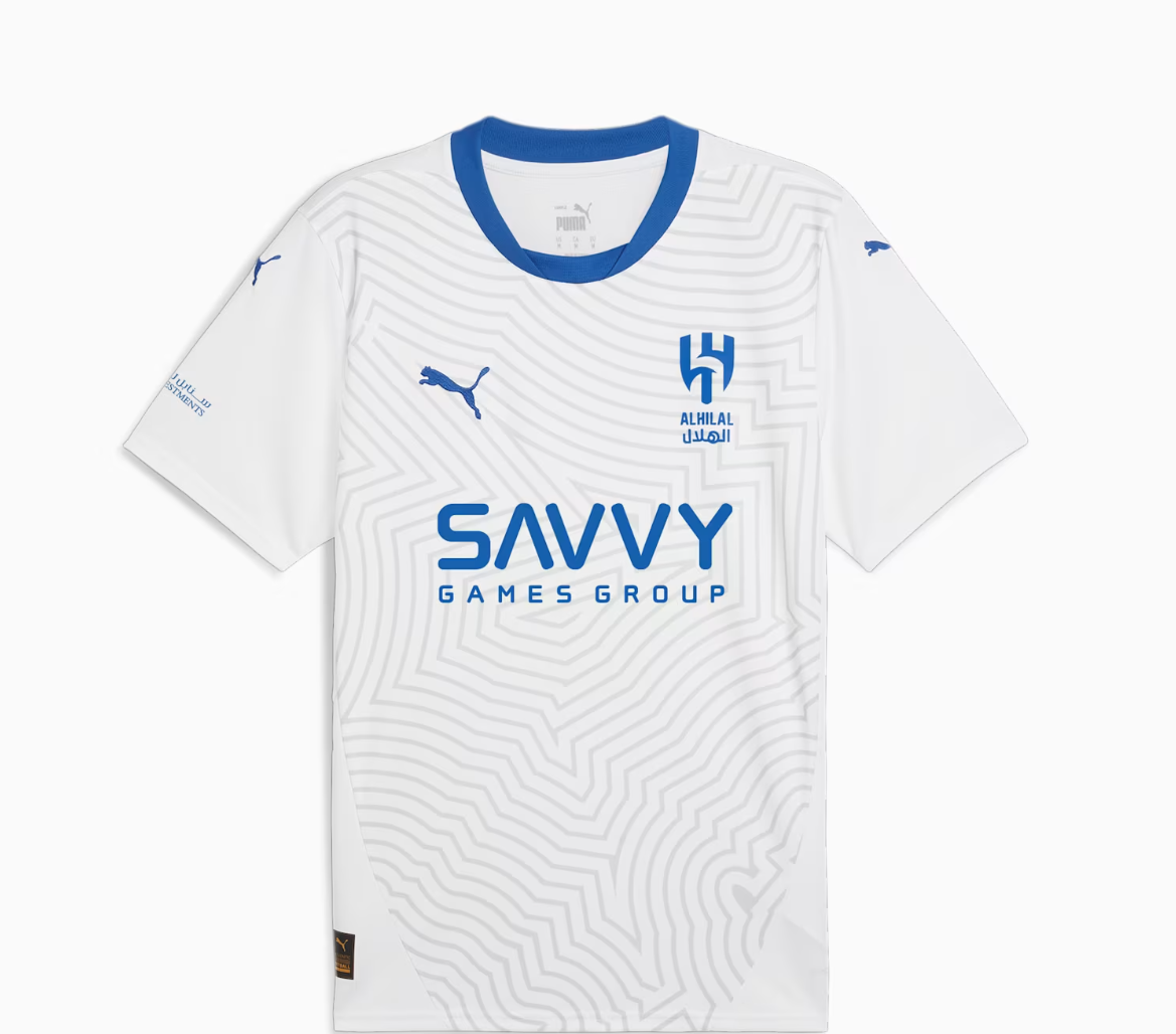 Screenshot_2024-09-04_203321 | UAE SPORT STORE White soccer jersey with blue crew neck and a subtle geometric pattern, featuring the blue Savvy Games Group sponsor across the chest and a blue club crest on the left chest with Puma branding on the sleeves.