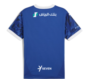 Back view of a blue sports jersey with white collar and cuffs, featuring geometric sleeve patterns and sponsor logos including Arabic text near the top and 'SEVEN' at the lower back area.
