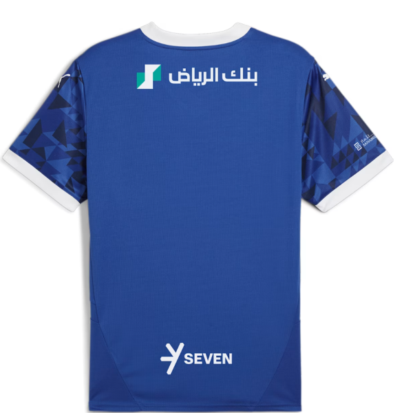 Back view of a blue sports jersey with white collar and cuffs, featuring geometric sleeve patterns and sponsor logos including Arabic text near the top and 'SEVEN' at the lower back area.