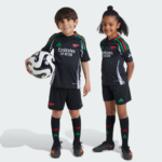 Two children in black Arsenal youth soccer kits stand side by side, one holding a soccer ball against a light background.