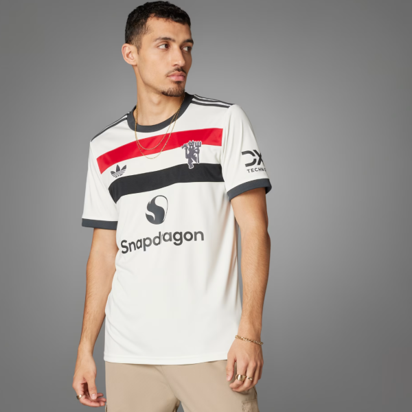 Man posing in a white jersey with red and black stripes, Snapdragon logo, against a gray backdrop.