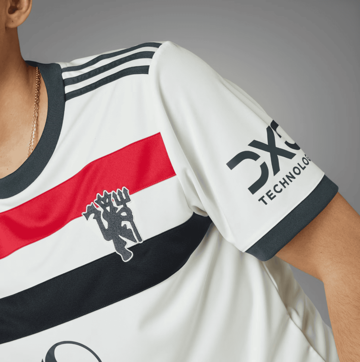 Close-up of a white athletic jersey with a red diagonal stripe, black trim, three shoulder stripes, and a partial logo on the sleeve reading TECHNOLOGY.