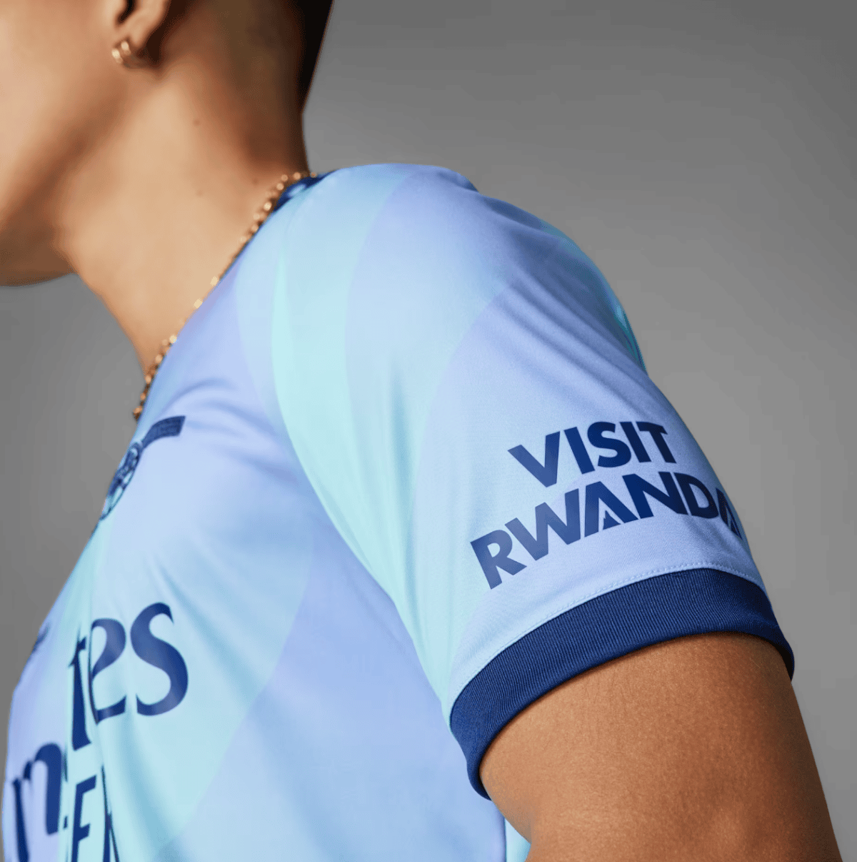 Close-up of a person wearing a light-blue sports jersey with 'VISIT RWANDA' on the sleeve.