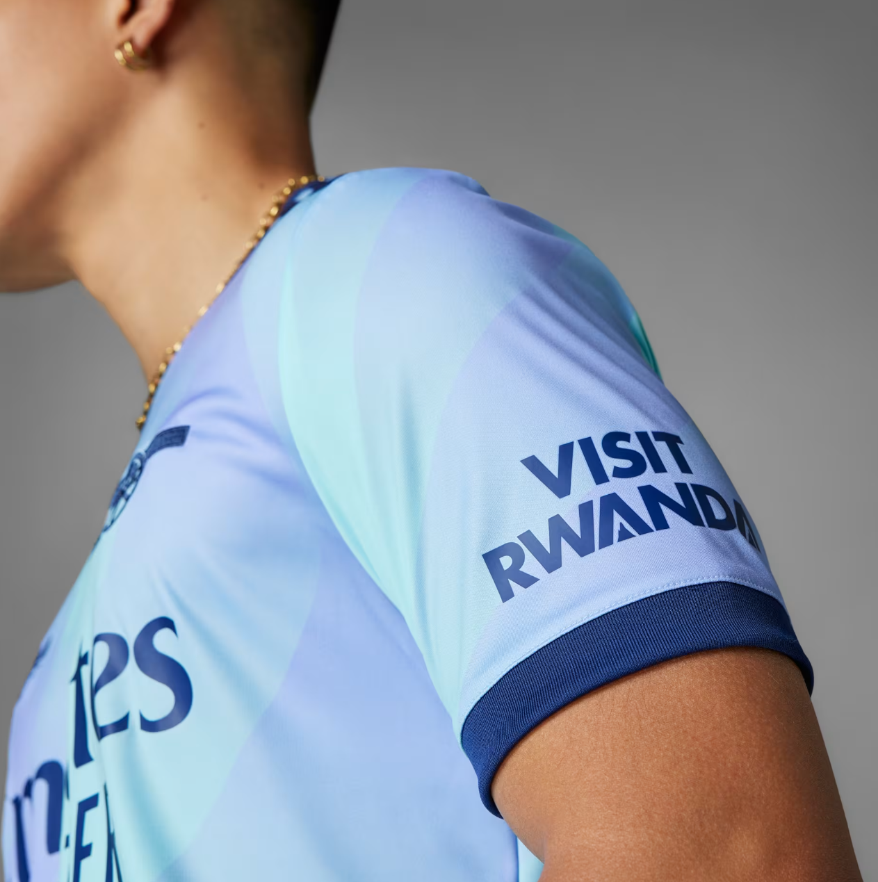 Screenshot_2024-09-18_194356_0370ebe5-2754-4438-9142-12157927cbb6 | UAE SPORT STORE Close-up of a person wearing a light-blue sports jersey with 'VISIT RWANDA' on the sleeve.