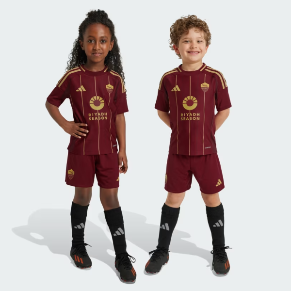 Two kids in maroon soccer kits with matching shorts, standing side by side wearing Riyadh Season jerseys and black socks.