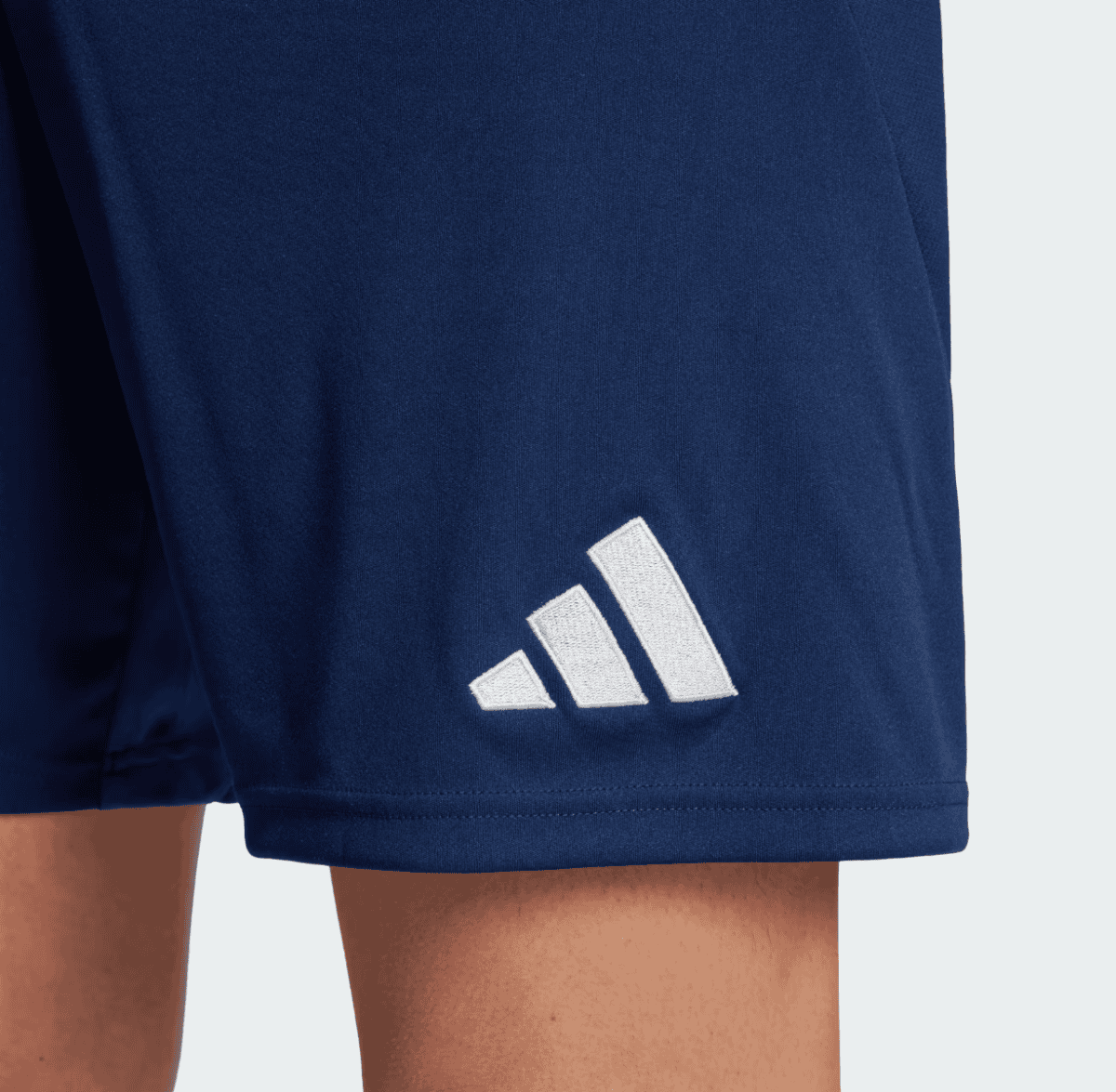 Close-up of navy athletic shorts hem with a white Adidas logo (three striped emblem).