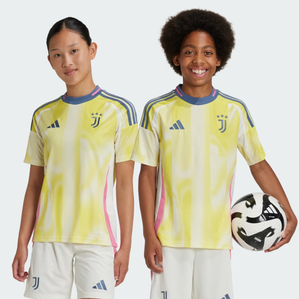Two kids in bright yellow Juventus soccer jerseys stand side by side; one holds a soccer ball and smiles at the camera.