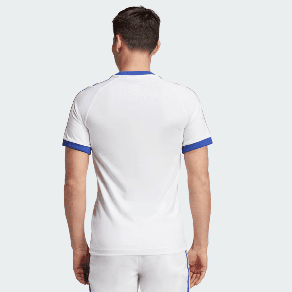 Back view of a man wearing a white athletic T-shirt with blue collar and sleeve cuffs
