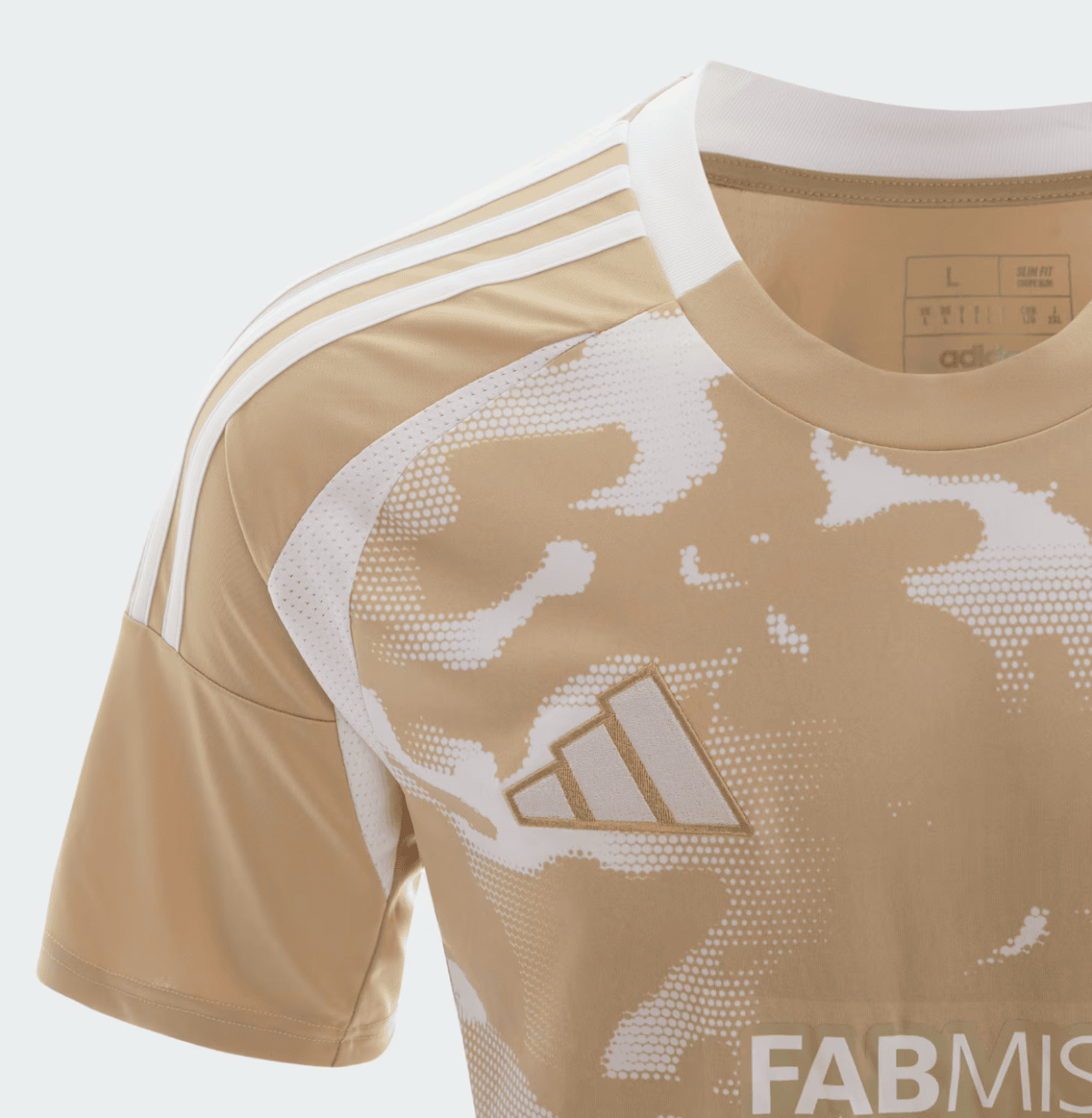 Close-up of a tan Adidas sports jersey with white three-stripe shoulder, white camo pattern, and a gold Adidas logo on the chest.