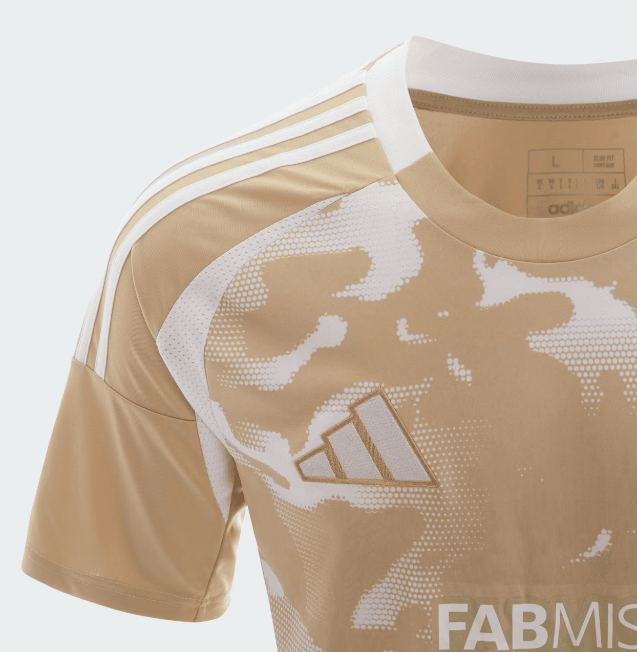 Screenshot_2025-01-14_174441 | UAE SPORT STORE Close-up of a tan Adidas sports jersey with white three-stripe shoulder, white camo pattern, and a gold Adidas logo on the chest.