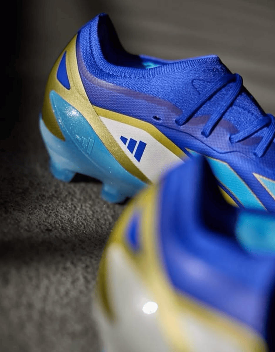 Screenshot_2025-01-21_184659 | UAE SPORT STORE Blue and yellow soccer cleat with white panel, close-up on the heel and laces.