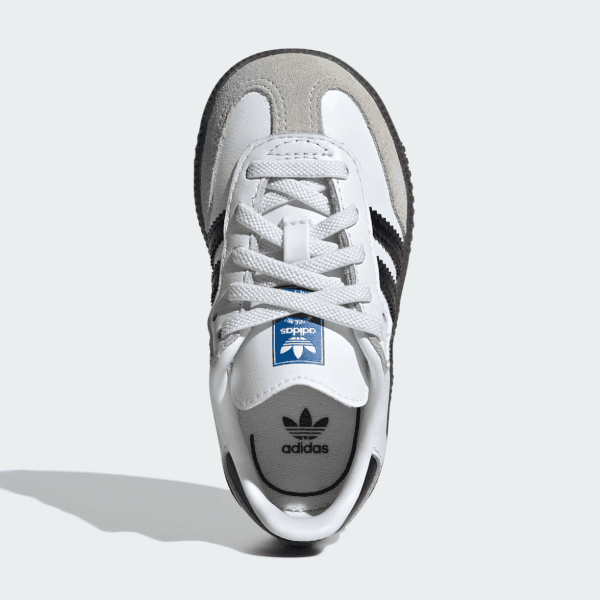 Top-down view of a white Adidas sneaker with gray toe cap and black stripes on the side.