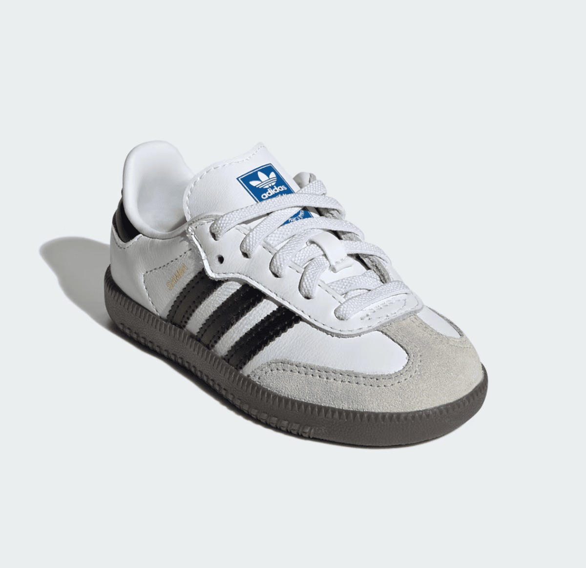 White Adidas Samba sneaker with black stripes and gray sole on a pale background, toe suede cap visible.
