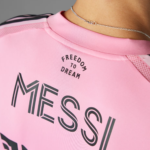 Close-up of a pink athletic shirt with the curved text 'FREEDOM TO DREAM' and a silver necklace visible at the neckline.