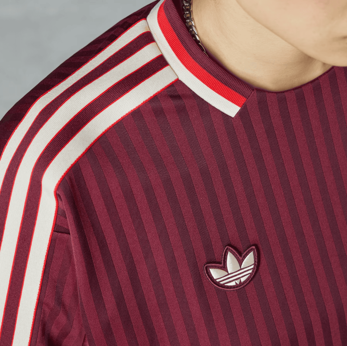 Maroon striped shirt with white and red shoulder stripes and an Adidas trefoil logo on the chest near the collar.