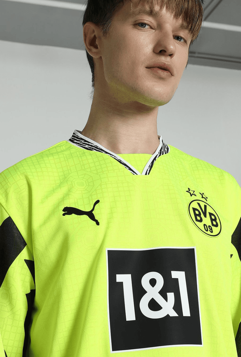 Screenshot_2025-04-13_053235 | UAE SPORT STORE Young man wearing a neon Borussia Dortmund goalkeeper jersey with the club crest and 1&1 sponsor, captured from chest up in a studio setting.
